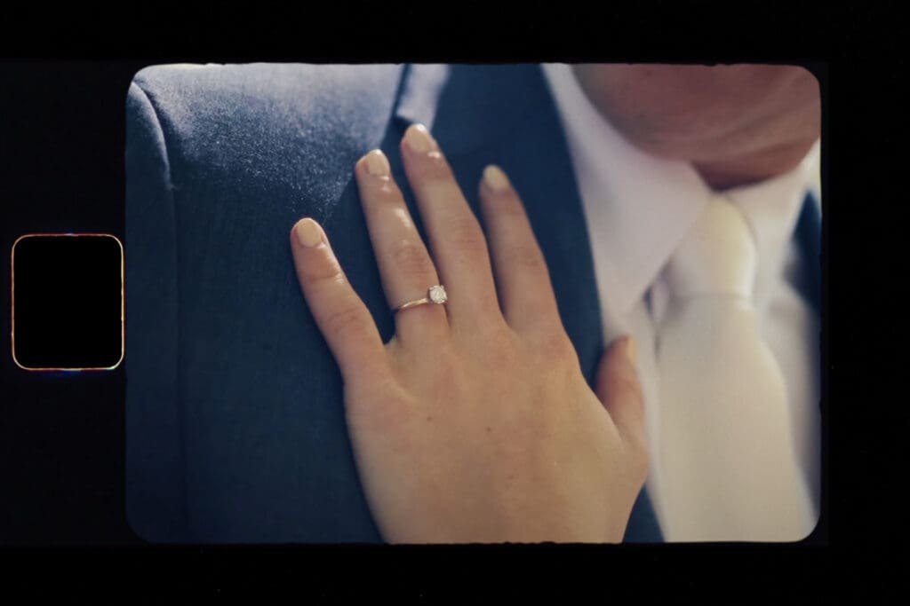 Close-up engagement photos showing a hand with a diamond engagement ring resting on a partner’s shoulder, with a soft, romantic background.